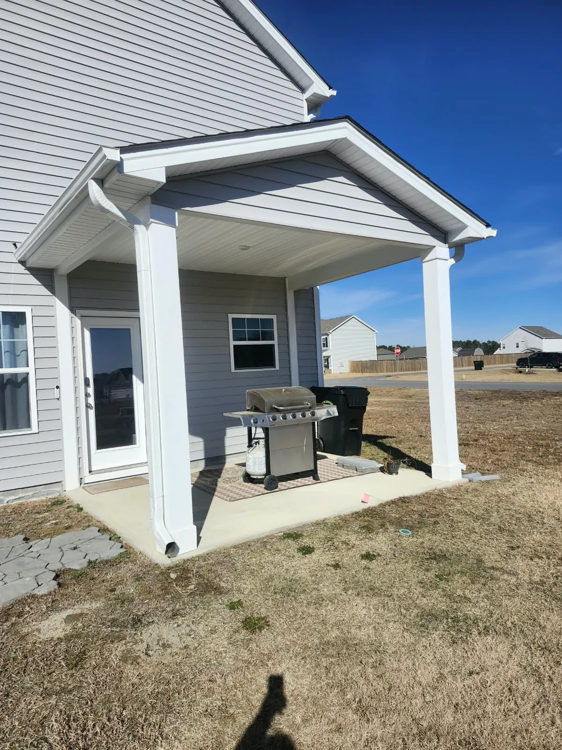 Covered back porch on white columns over a new concrete slab