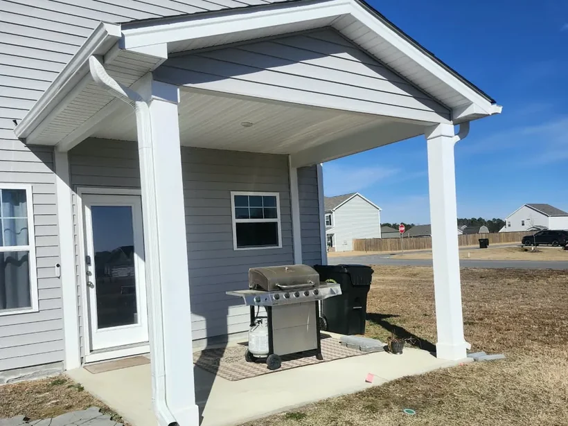 Covered back porch on white columns over a new concrete slab
