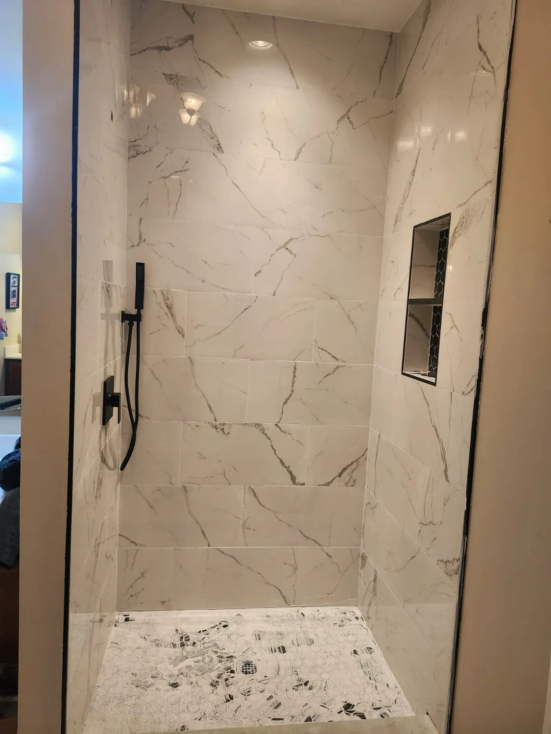 Walk-in shower tiled floor to ceiling in marble-look porcelain