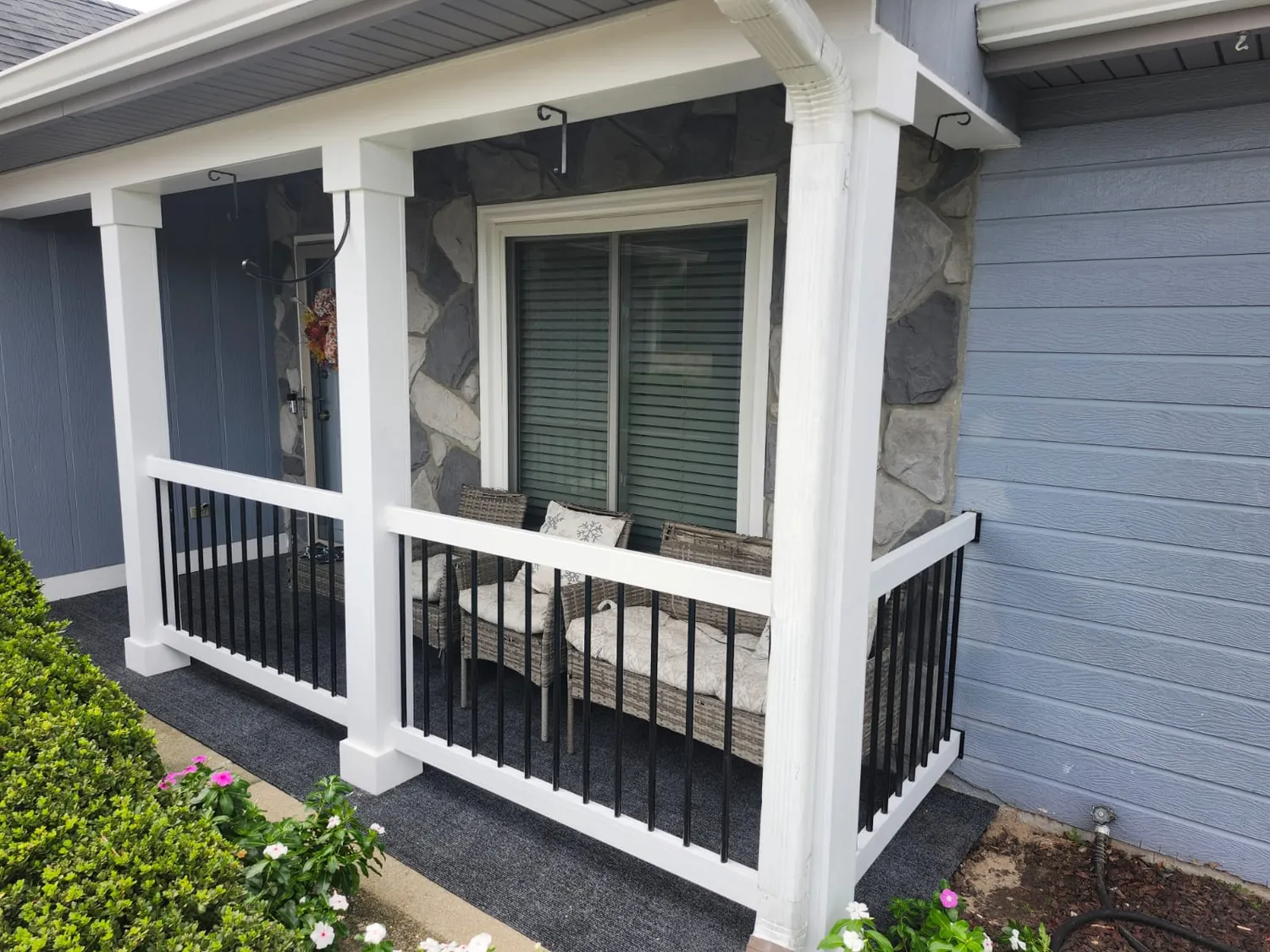 Front porch with stone column bases and black metal railing